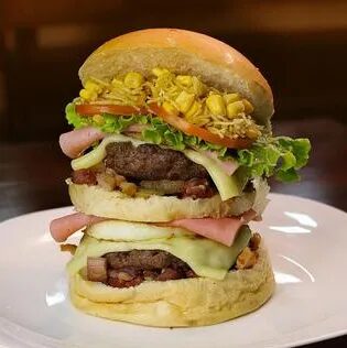 Hambúrguer duplo com milho, alface e tomate servido no prato